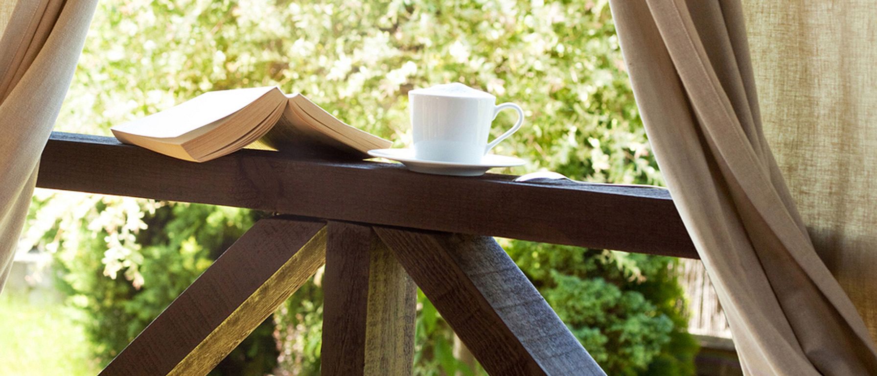 Book, cup of tea at a window showing nature outside