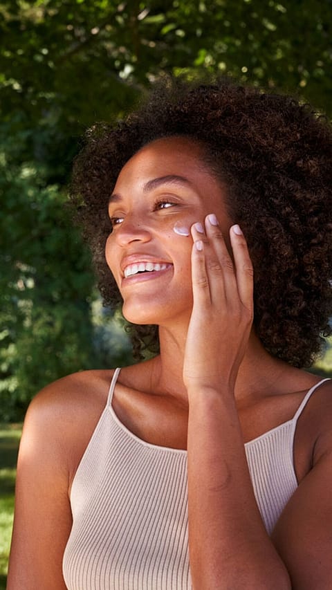 Woman creaming her face in nature
