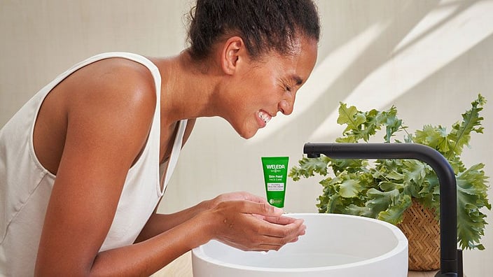 Woman cleaning her face over the sink with skinfood cleaning balm